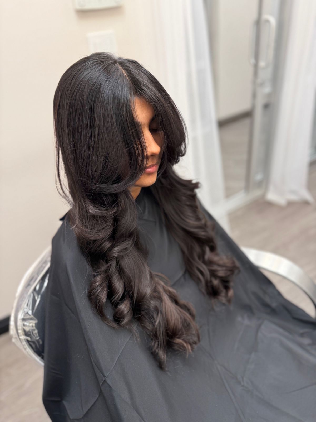 Cabello oscuro estilizado con rizos voluminosos y capas